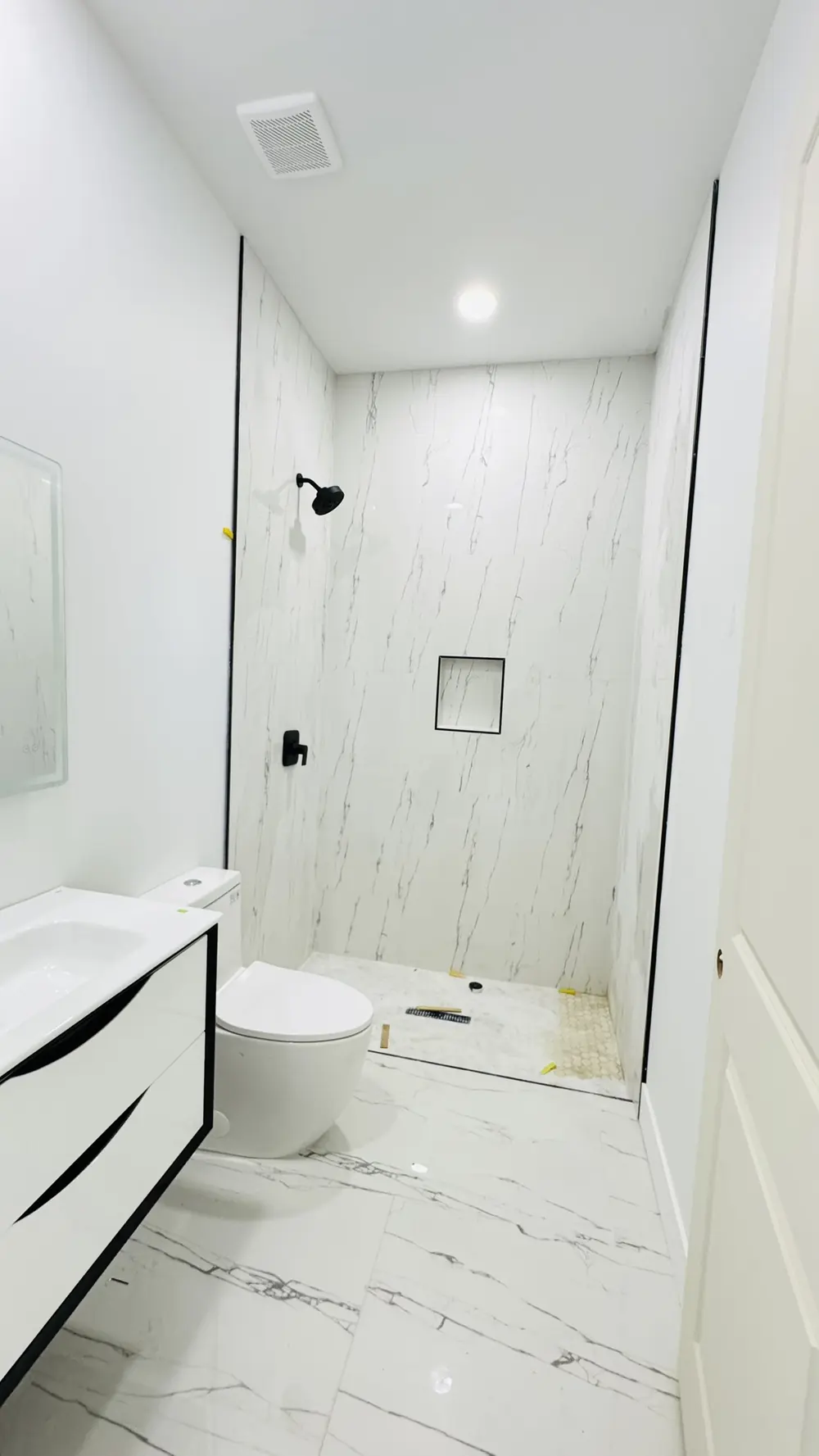 Bathroom with marble-look tiled walk-in shower and floating vanity