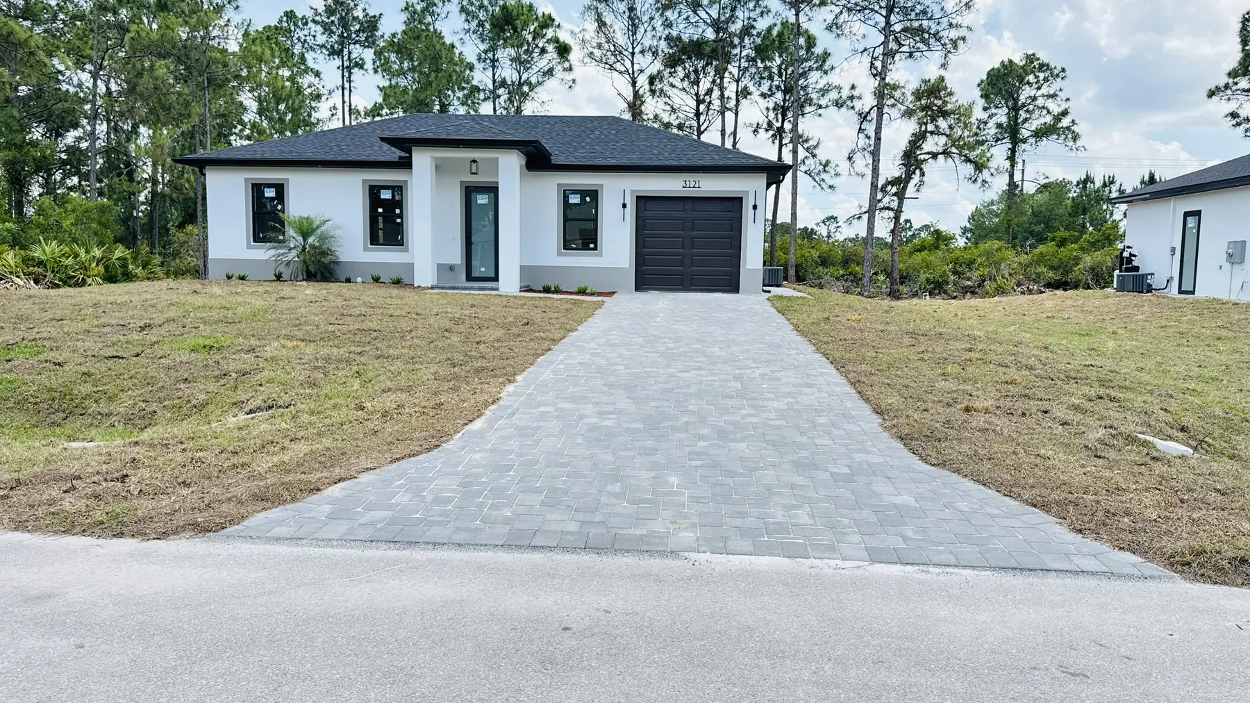 Finished home with a long gray paver driveway