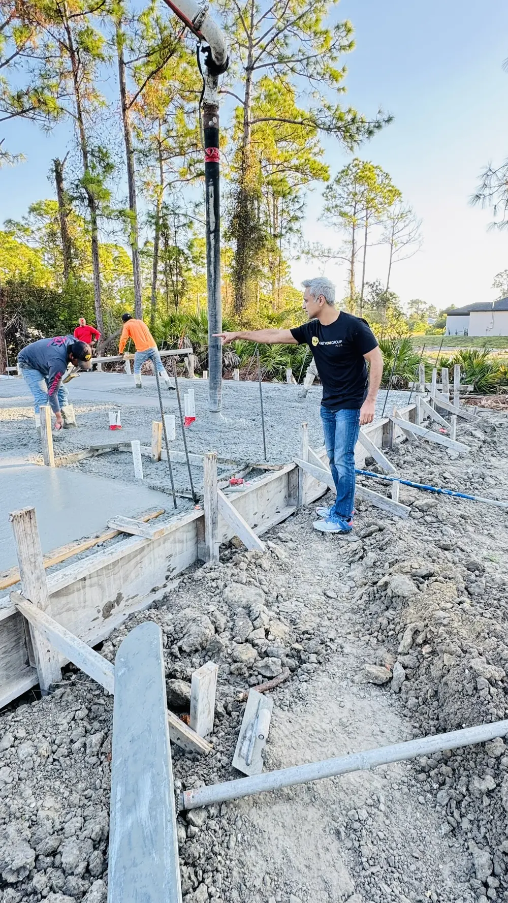 Crew pouring the concrete slab while a partner directs